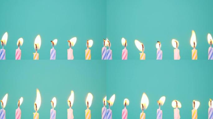 生日快乐概念由在蓝色或绿松石背景上燃烧五颜六色的蜡烛制成。燃烧7周年生日蜡烛。慢动作全高清视频
