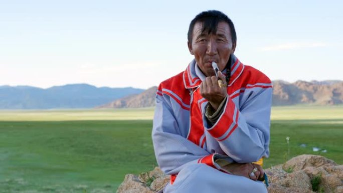 身着传统服饰的蒙古族牧民在西部阿尔泰山附近抽烟。