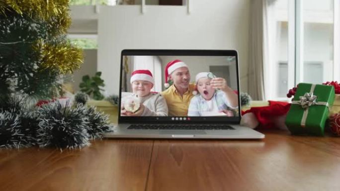 微笑的高加索家庭戴着圣诞老人的帽子在笔记本电脑上的圣诞节视频通话中