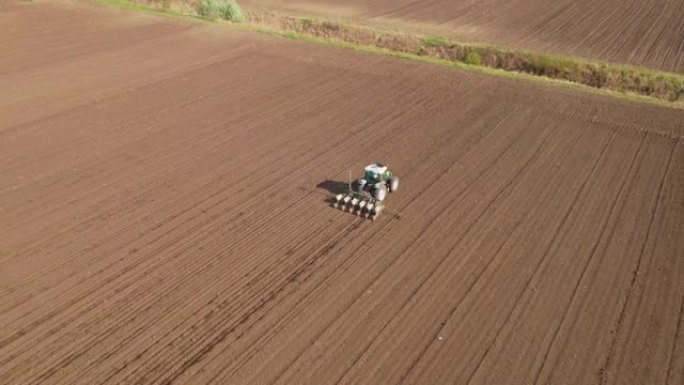 农民在耕地上用拖拉机播种大豆