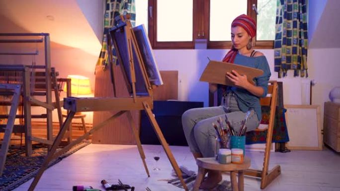 在她舒适的艺术工作室里，城市女艺术家用油画在画布上绘画