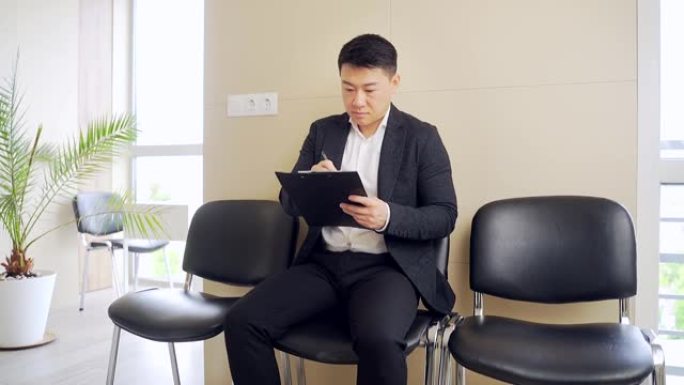 穿着商务正装的亚洲年轻人在候诊室参加结果面试或会议。办公室里的商业男性