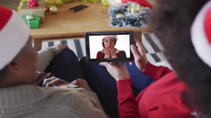 非裔美国母亲和女儿使用平板电脑与屏幕上的女人进行圣诞节视频通话
