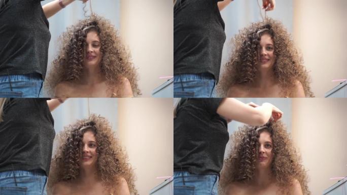 特写一位卷发的美女，她的头发正在整理，她笑着看着镜头