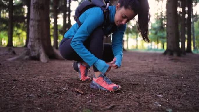 活跃而健康的年轻女子，在森林徒步旅行时系着她的跑步运动鞋