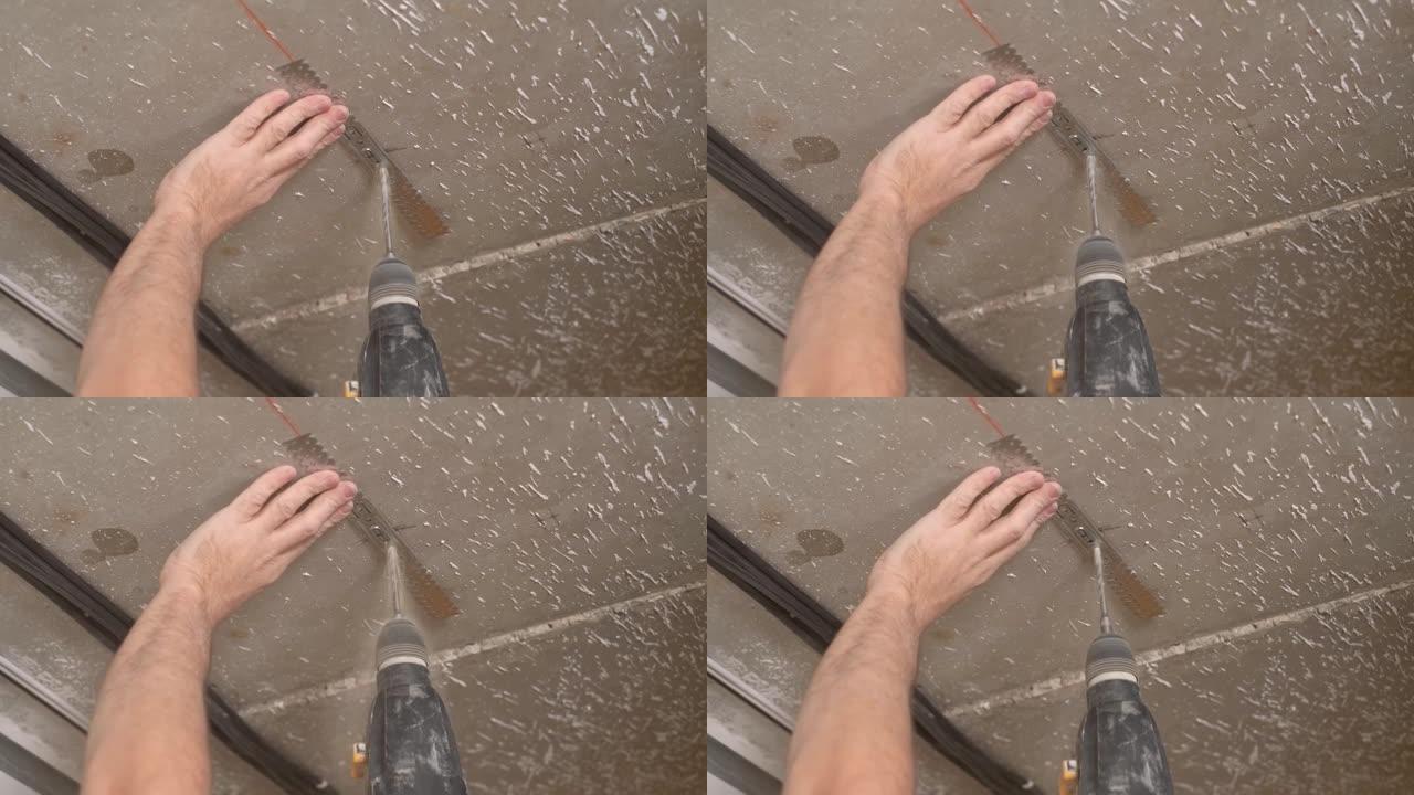 工人用锤钻在天花板上钻一个孔，以安装天花板型材固定。石膏板天花板的安装。建筑物的翻新或改建。特写，现