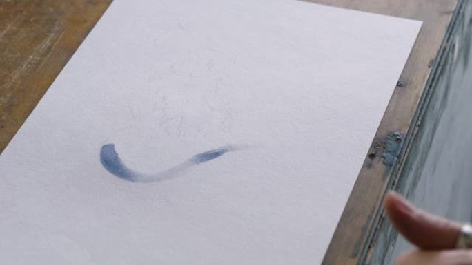 女性手在艺术工作室用画笔画水彩画蓝色的心。4K