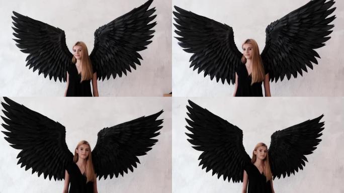 黑色天使翅膀和白色背景上的黑色连衣裙的女孩。