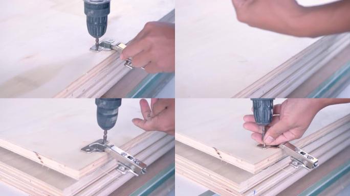 工匠的手用螺钉将橱柜铰链安装在木制橱柜门上。有技巧