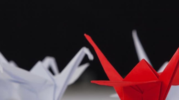 一只红色的折纸天鹅在白色的折纸天鹅中间