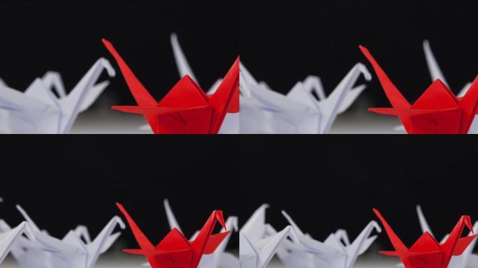 一只红色的折纸天鹅在白色的折纸天鹅中间