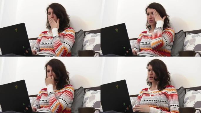 一个女人坐在她的床上，使用她的笔记本电脑，在屏幕上看到一个可怕的场景，并做出情绪反应。