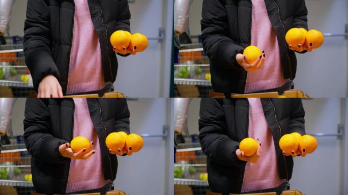 女孩的手在大卖场的货架上选择新鲜的橙子。选择性聚焦