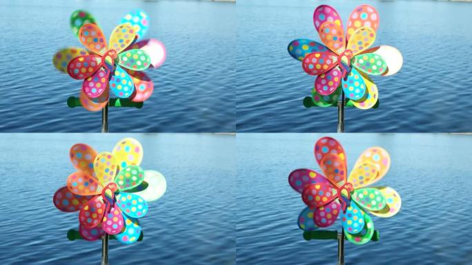 公园里的儿童彩色风车玩具靠着蓝色的池塘