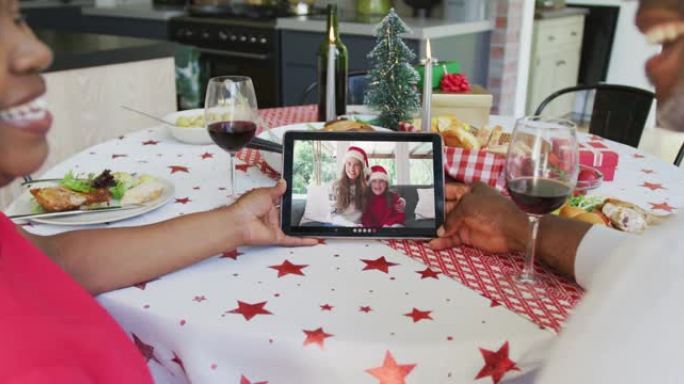 微笑的非洲裔美国夫妇使用平板电脑与屏幕上的幸福家庭进行圣诞节视频通话