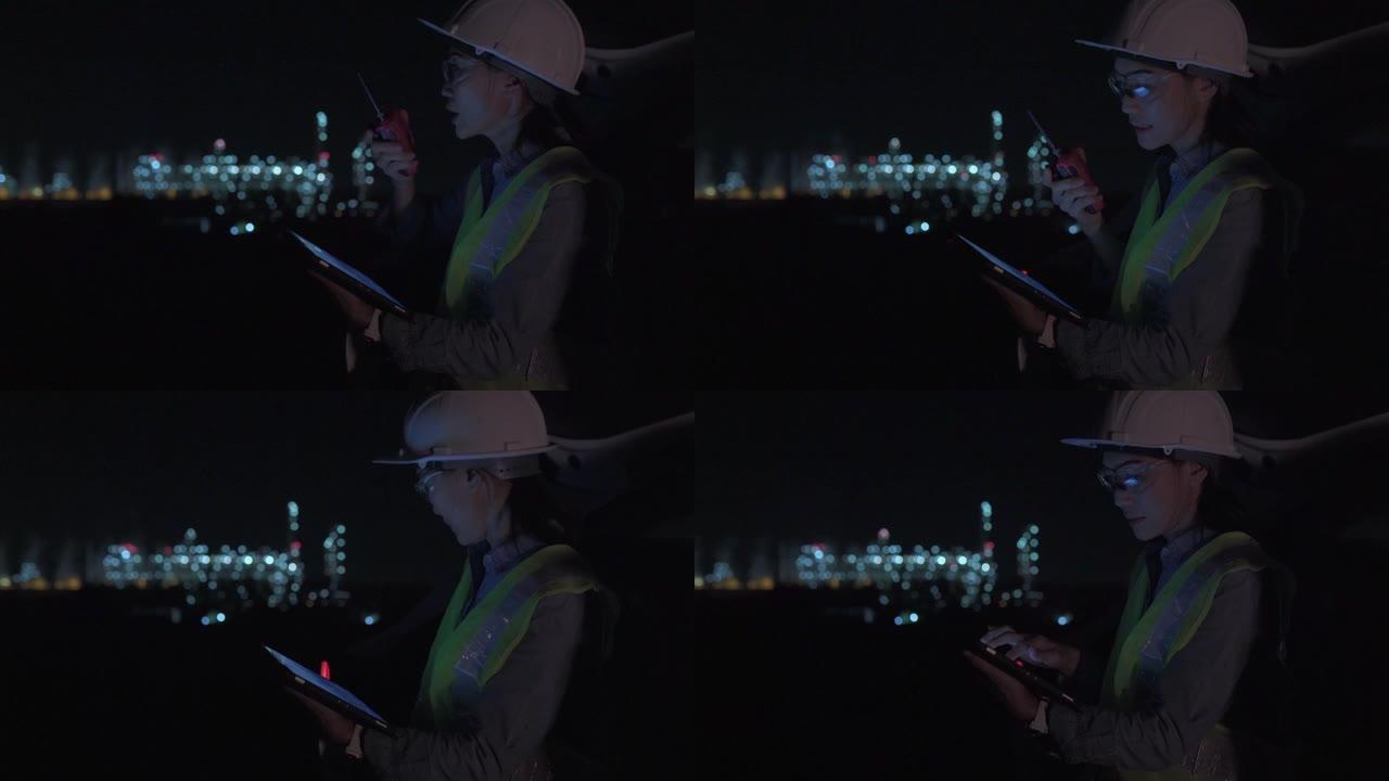 穿着制服的女主管使用数字平板电脑在工业区的石油炼油厂工作深夜