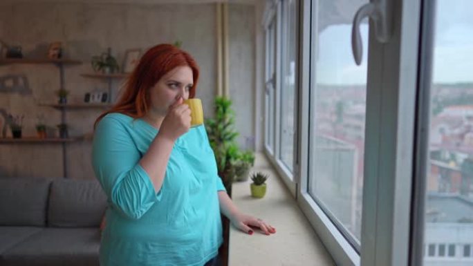 沮丧的女人正透过窗户看，喝着咖啡