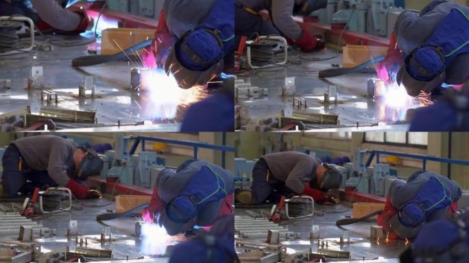 火车工厂的两名焊工焊接在不锈钢轨道车上-缩小镜头