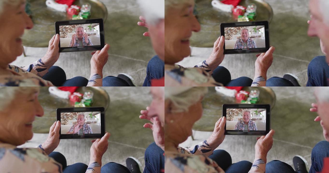 白人高级夫妇微笑着使用平板电脑与屏幕上的男人进行圣诞节视频通话