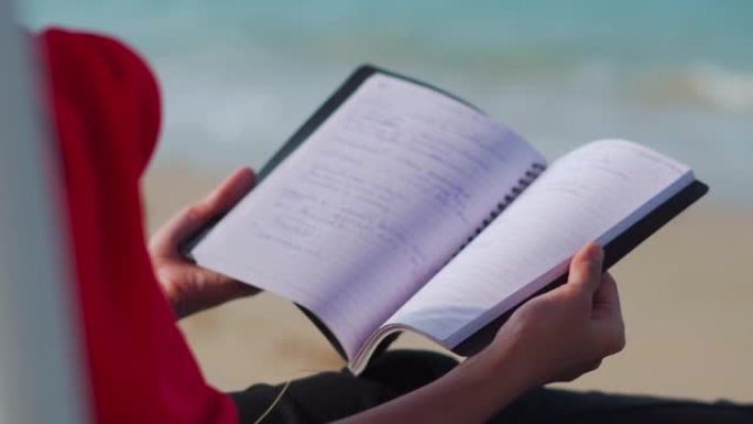 在海滩海浪的背景下，女人翻页的特写镜头。夏季海滩放松的概念