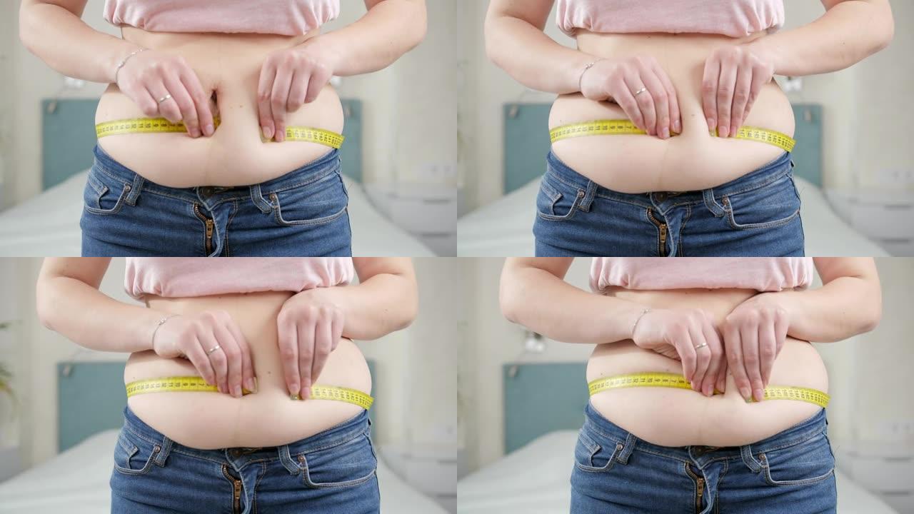 体重过重的年轻胖女人用卷尺测量她的大肚子。节食的概念，不健康的生活方式，超重和肥胖