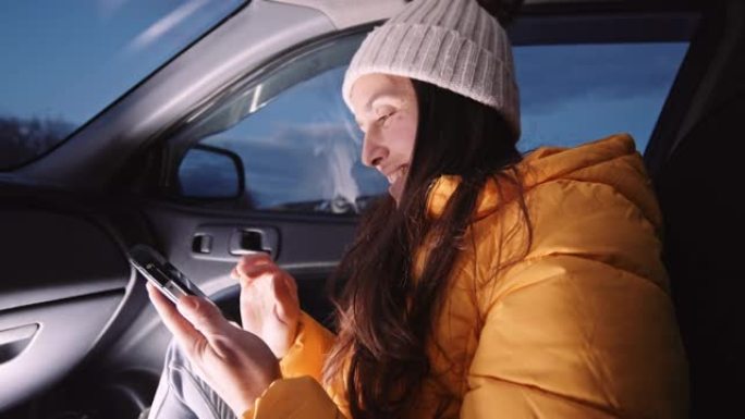 微笑的女人在汽车上浏览婴儿的照片。