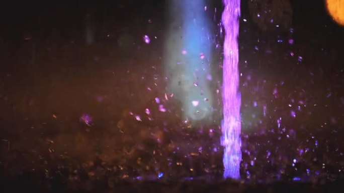 五颜六色的喷泉飞溅。以各种颜色照亮的水的慢动作落在喷泉上，该喷泉在夜间改变了其水色。