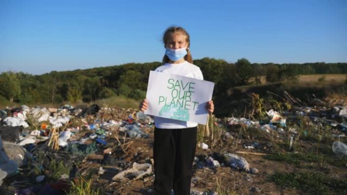 小女孩手持环保运动拯救地球的标语牌。医用防护口罩的小型女性生态志愿者倡导在肮脏垃圾场的背景下进行自然