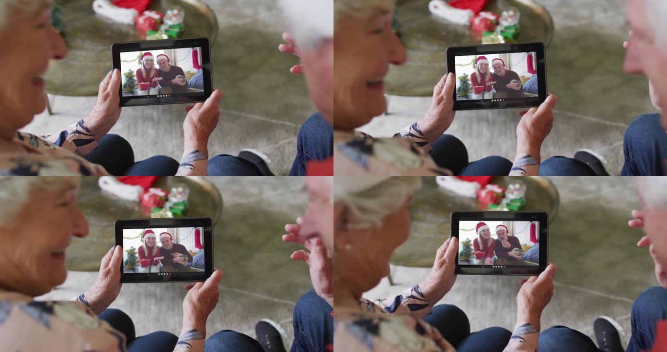 微笑的白人高级夫妇使用平板电脑进行圣诞节视频通话，屏幕上的夫妇