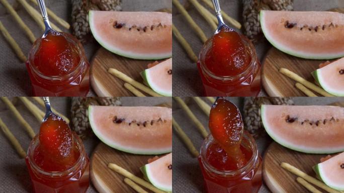 用勺子从玻璃罐中取出红色果酱，显示出果酱的质地。自然相机抖动。