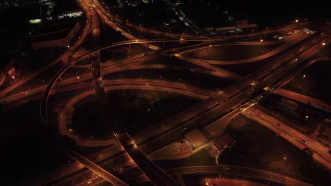 城市中的高速公路交界处，夜间有交通的高速公路的头顶镜头，鸟瞰图