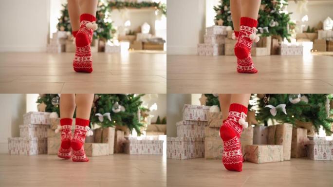 穿着红色新年袜子的女腿走路用礼物装饰圣诞树