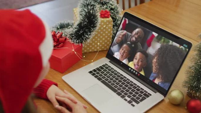 白人妇女在屏幕上与非裔美国人家庭在笔记本电脑上进行圣诞节视频通话