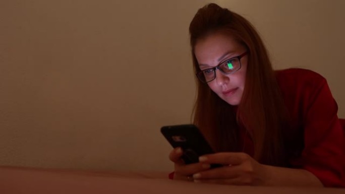 女人躺在床上在手机屏幕上打字文本，在社交网络上聊天