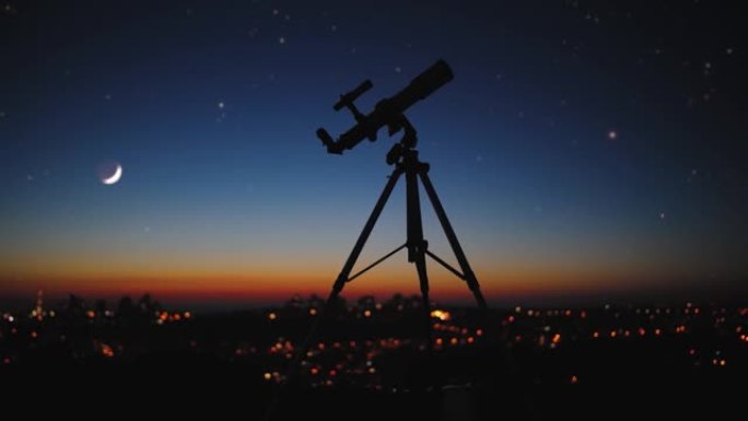 星空下的望远镜和城市灯光的轮廓。