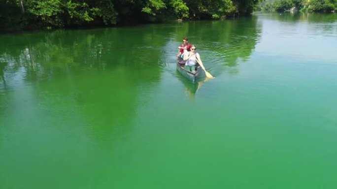 夏季，情侣在绿色野河划独木舟的空中拍摄。旅行未受影响的自然假期概念。