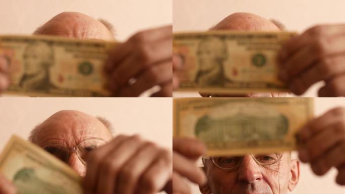 一位70岁的白人老人戴着眼镜，仔细检查了一张10美元的钞票。假钱主题。一个人手中的10美元。选择性聚