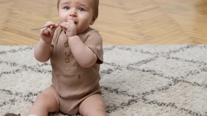 探索世界的孩子。可爱的小宝宝玩茶匙，坐在家里的地毯上，慢动作，自由空间