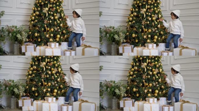 穿着白色毛衣和帽子的男孩站在圣诞树上