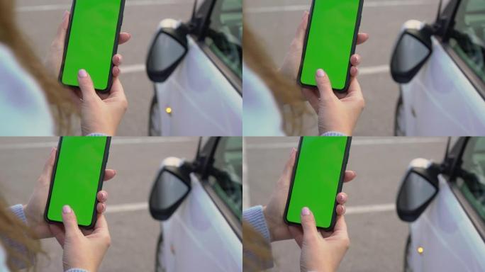 带移动绿屏的女孩在停车场拍照。车祸破碎的镜子