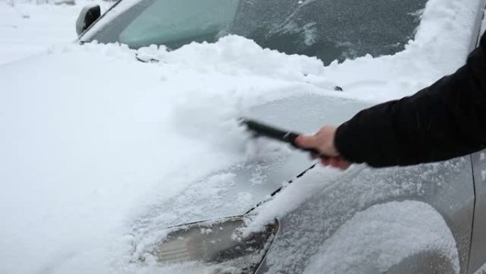 暴风雪暴风雪后，人从车窗上刷新鲜的雪。冬季寒冷天气车主的早晨常规困难。车窗清洁。冬季。白雪。车辆保养