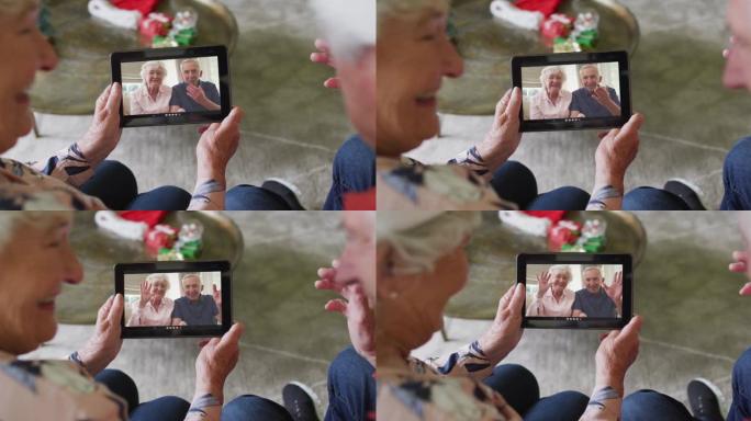 高级高加索夫妇使用平板电脑与屏幕上的幸福夫妇进行圣诞节视频通话