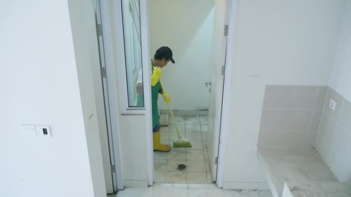 男性看门人用扫帚打扫房子内部