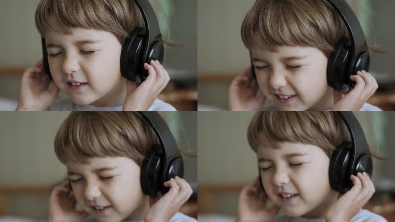 孩子戴着耳机闭着眼睛放松时的慢动作。孩子在家听音乐。戴着耳机听音乐的可爱的小男孩的肖像。快乐无忧无虑