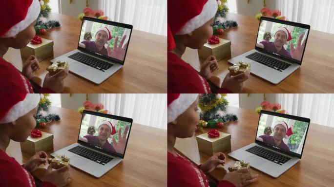 戴着圣诞老人帽子的非洲裔美国妇女使用笔记本电脑进行圣诞节视频通话，屏幕上有男人