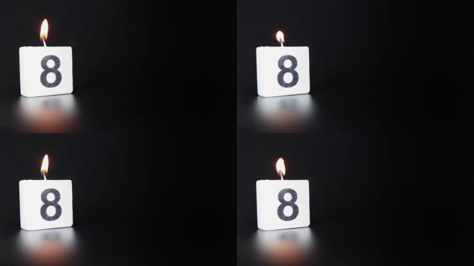 一根方形蜡烛，上面写着数字8被点燃并吹出，庆祝生日或周年纪念日。