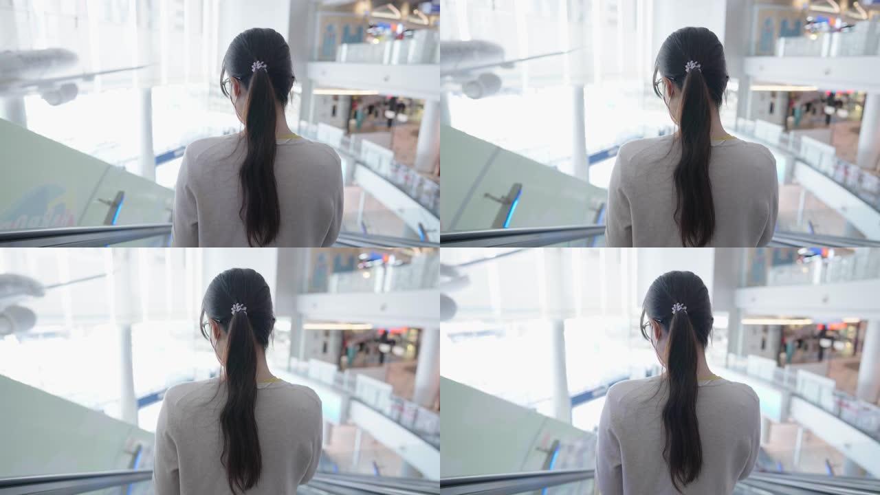 一名戴着药用口罩的亚洲中年妇女带着智能手机在购物中心散步