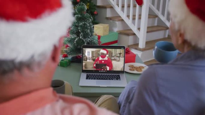 圣诞节时，快乐的高级高加索夫妇在笔记本电脑上与圣诞老人戴着口罩进行视频通话