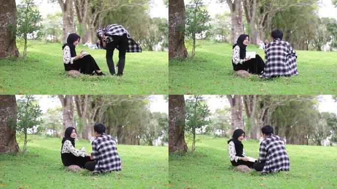 年轻夫妇坐在公园看书