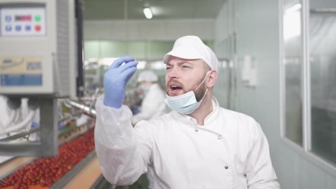微笑的男性在工厂的生产线上检查填充的辣椒